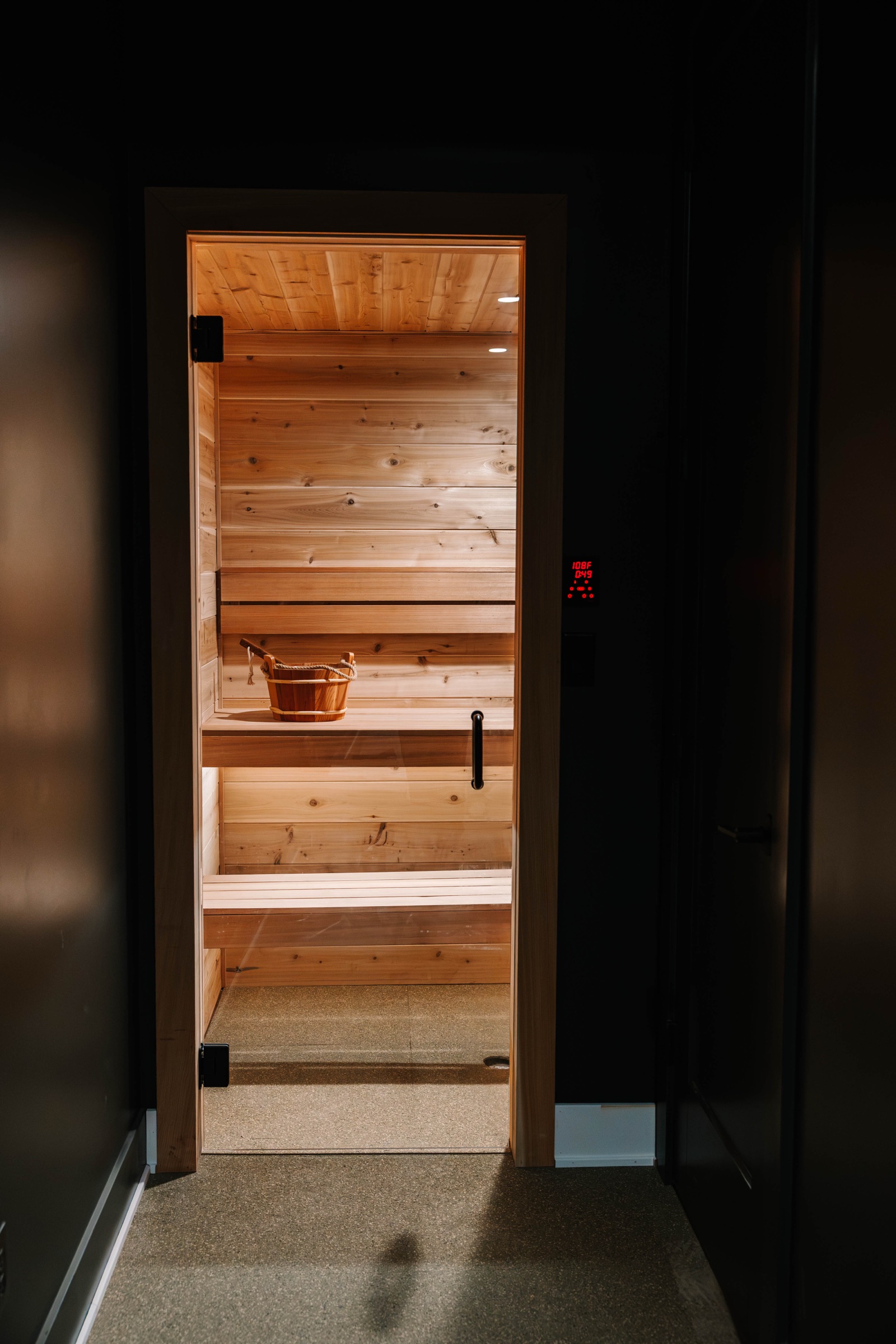 A glowing cedar sauna seen through a dark doorway